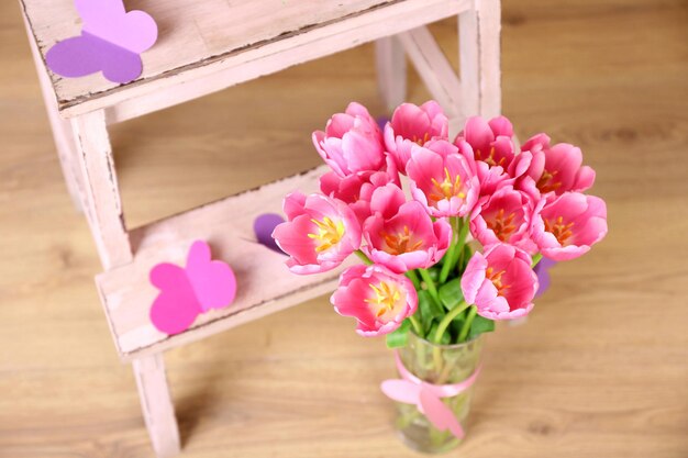 Composição com buquê de tulipas em vaso, na escada, no fundo da parede