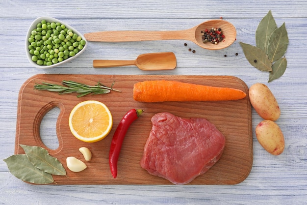 Foto composição com carne e legumes na tábua de madeira