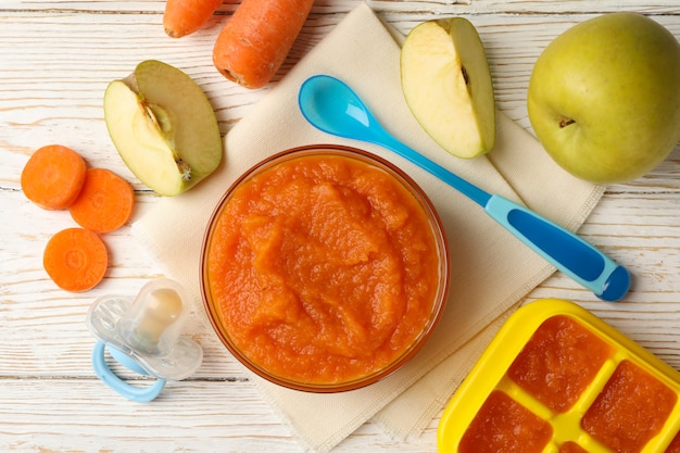 Foto composição com comida para bebê no fundo branco de madeira