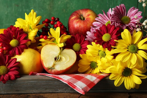 Foto composição com crisântemo e frutas na mesa de madeira