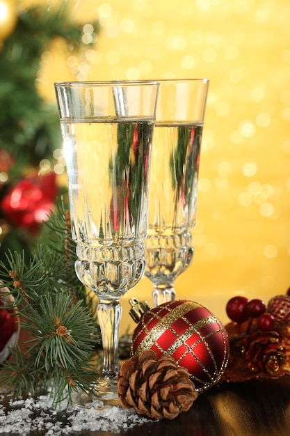 Foto composição com decorações de natal e duas taças de champanhe, em fundo brilhante
