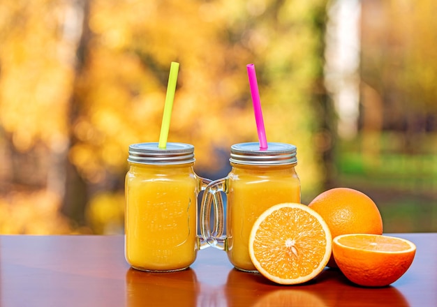 Composição com dois copos de suco de laranja espremido na hora e fatias de laranjas maduras