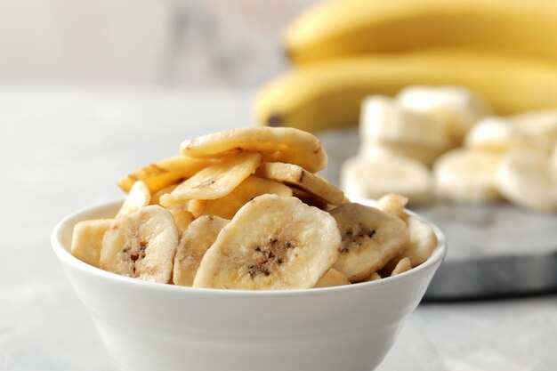 Composição com fatias de banana secas doces, bananas frescas em um fundo de madeira de mármore. frutos secos como lanche saudável