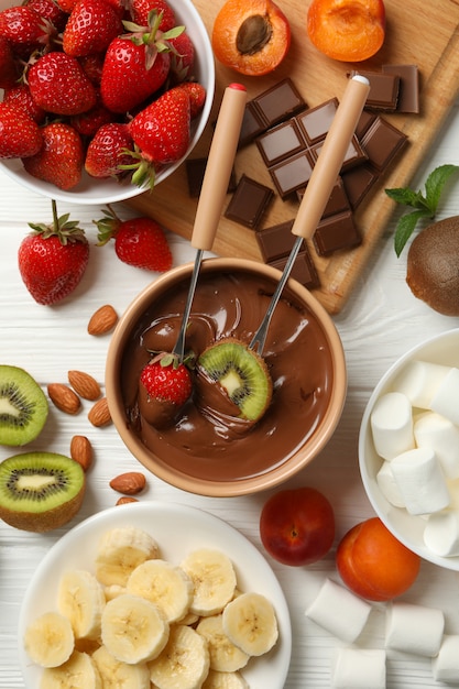 Composição com ingredientes para fondue de chocolate no fundo branco de madeira. Fondue de cozinha