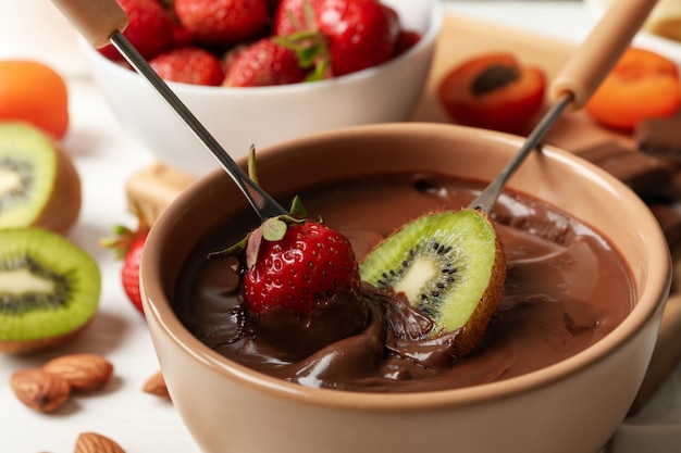 Composição com ingredientes para fondue de chocolate no fundo branco de madeira. Fondue de cozinha