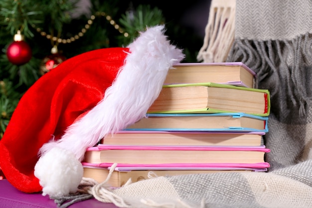 Foto composição com livros e xadrez, chapéu vermelho, na cadeira na árvore de natal