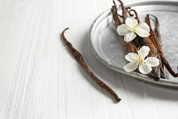 Composição com palitos de baunilha secos em uma mesa de madeira clara, close-up