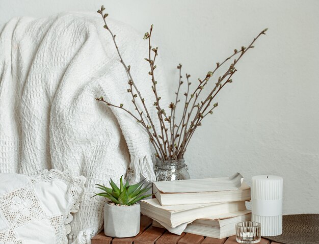 Composição com ramos de primavera, livros e velas no interior da sala.