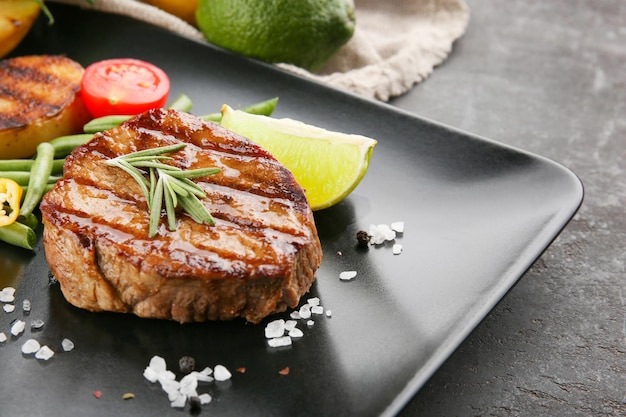 Composição com saboroso bife grelhado e legumes na mesa fechada