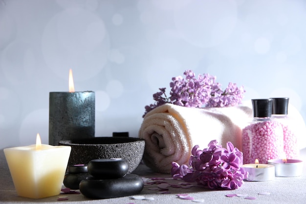 Composição com toalhas de tratamento de spa e flores lilás na mesa de madeira sobre fundo claro