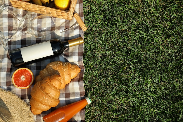Composição com vinho, croissants, frutas e toalha na grama