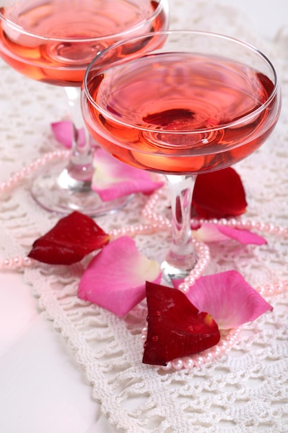 Composição com vinho rosa em copos e pétalas de rosa isoladas em branco