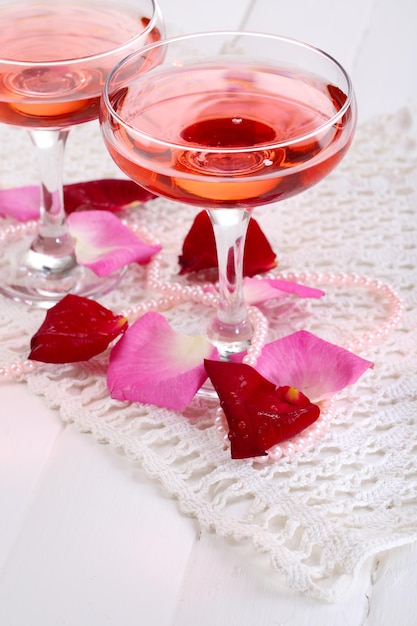 Composição com vinho rosa em copos e pétalas de rosa isoladas em branco