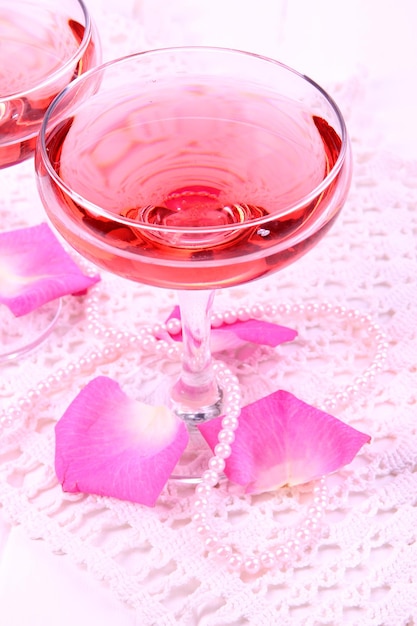 Composição com vinho rosa em copos e pétalas de rosa isoladas em branco