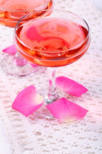 Composição com vinho rosa em copos e pétalas de rosa isoladas em branco