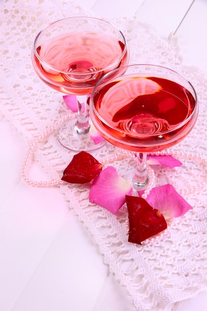 Composição com vinho rosa em copos e pétalas de rosa isoladas em branco