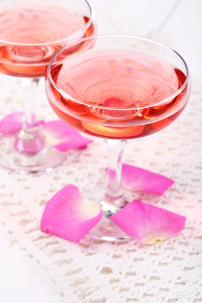 Composição com vinho rosa em copos e pétalas de rosa isoladas em branco