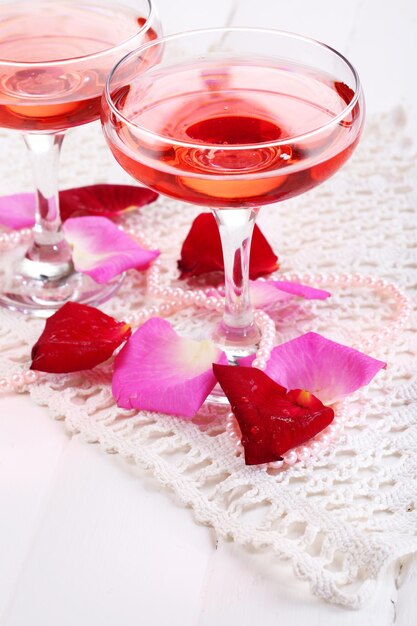 Composição com vinho rosa em copos e pétalas de rosa isoladas em branco