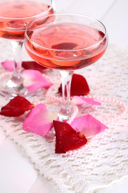 Composição com vinho rosa em copos e pétalas de rosa isoladas em branco