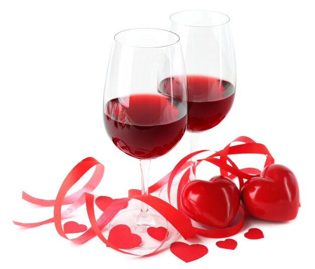 Composição com vinho tinto em copos, rosas vermelhas, fita e corações decorativos isolados em branco