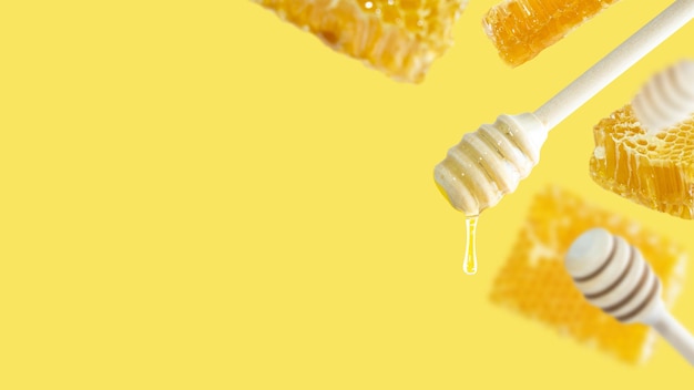 Composição conceitual de mel com espaço para texto um conjunto de conchas de mel com gota de mel e pedaços de favo de mel flutuando em um fundo amareloa imagem de comida naturaldesign de layout criativo