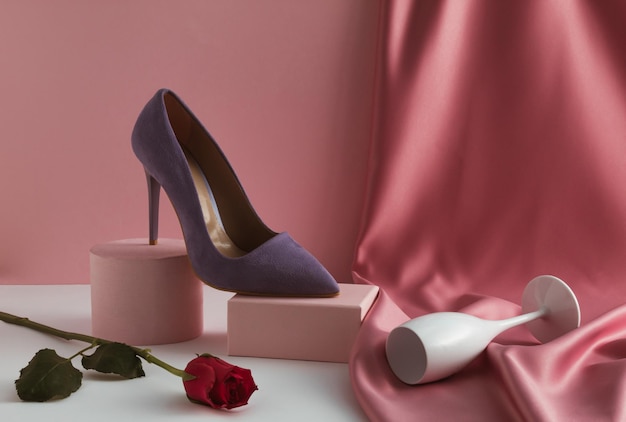 Composição contemporânea com sapato roxo de salto alto de mulher elegante na flor rosa do pódio do produto