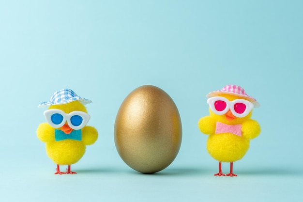 Composição criativa com ovo de páscoa de ouro e galinhas em fundo azul