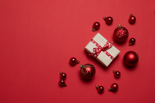 Composição criativa com presentes ou caixas de presentes com laços vermelhos, bolas vermelhas sobre fundo vermelho.