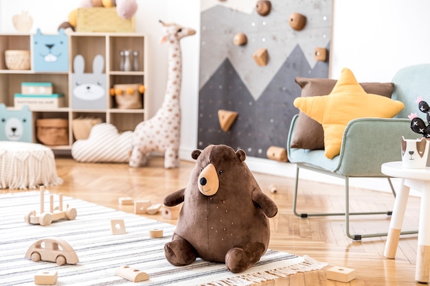 Composição criativa de interior elegante e aconchegante de quarto infantil com brinquedos de pelúcia sofá cômoda poltrona tapete e acessórios