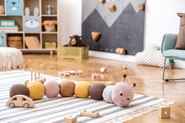 Foto composição criativa de interior elegante e aconchegante de quarto infantil com brinquedos de pelúcia sofá cômoda poltrona tapete e acessórios