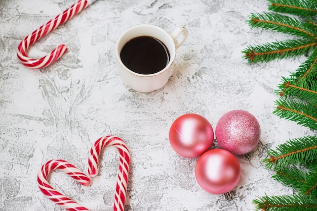 Composição de ano novo ou Natal de ramos verdes de abeto, bolas de ano novo, café e pirulitos de Natal em um fundo textural brilhante. Camada plana, layout, moldura, espaço de cópia