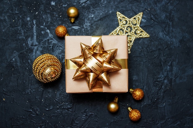 Foto composição de cartão de natal. presente com decoração de natal dourada sobre fundo azul escuro.