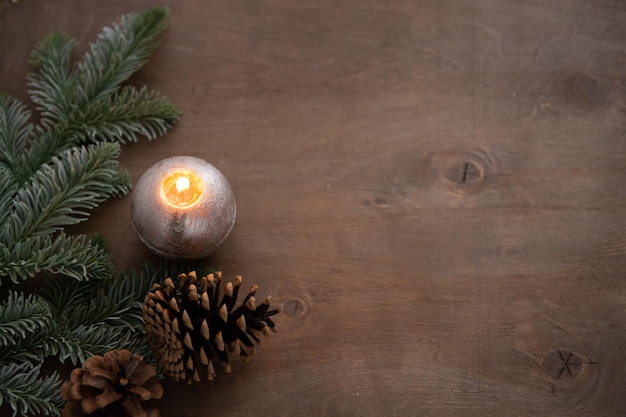 Composição de decoração de natal com cone de vela a arder e luzes sobre fundo de madeira natural