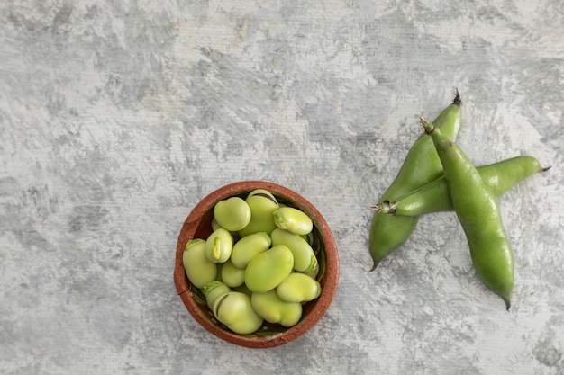 Composição de favas descascadas e descascadas em uma textura cinza e espaço de cópia