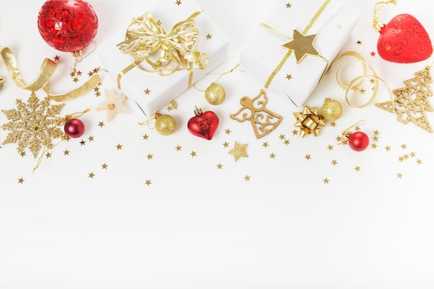 Composição de férias de Natal ou ano Ner. Padrão de ouro vermelho criativo festivo, bola de férias de decoração de ouro de Natal com fita, presente, flocos de neve, árvore de Natal em fundo branco. Camada plana, vista superior