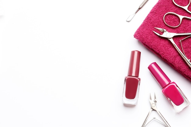 Composição de ferramentas para manicure, esmaltes, toalhas em um fundo branco com espaço para texto.