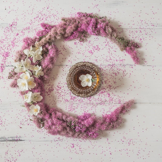 Composição de flores. círculo feito de flores cor de rosa com um copo de chá branco