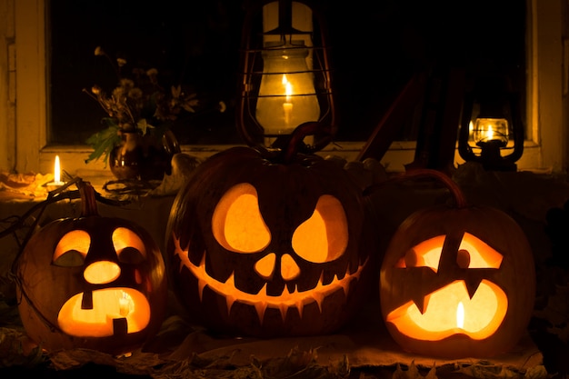 Composição de fotos de três abóboras no Halloween. Chorando, Jack e abóboras assustadas contra uma janela velha, folhas secas