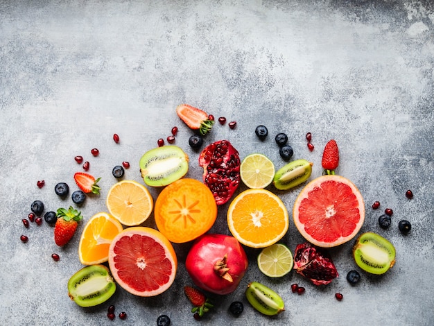 Foto composição de frutas naturais saudáveis sazonais multicoloridas com caqui, mirtilos, laranja, kiwi, morangos, toranja, romã, fatias de laranja. vista do topo