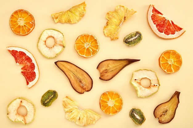Composição de frutos secos (kiwi, pera, tangerina, laranja, toranja, maçã) em colorido. Vista superior de frutas secas
