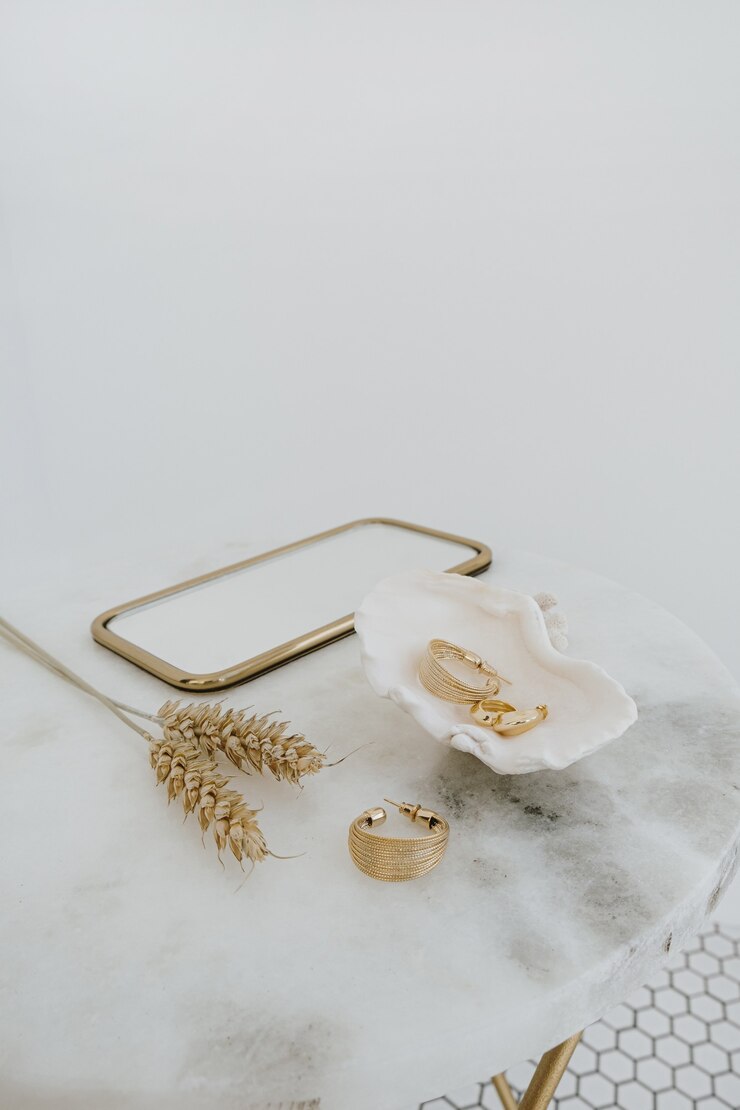 Composição de moda mínima com brincos de ouro em concha do mar na mesa de mármore com espelho e hastes de trigo. Conceito de joias da bijuteria.