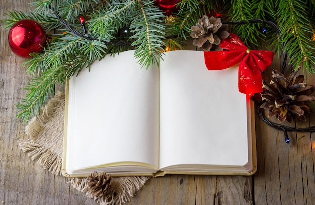 Foto composição de natal a partir de um caderno em branco aberto ramos de abeto com cones de pinheiro em um fundo de madeira