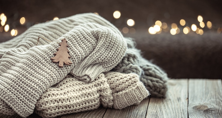 Foto composição de natal aconchegante com uma pilha de camisolas de malha em um fundo desfocado com bokeh.