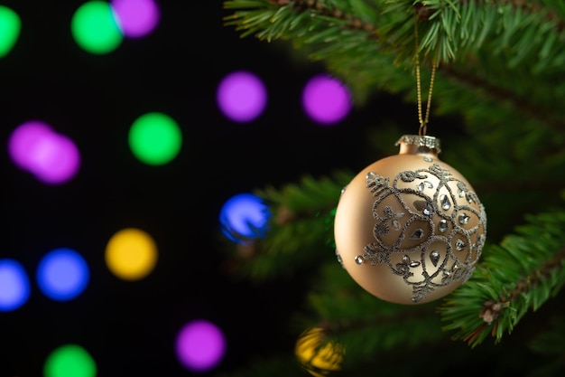 Foto composição de natal bela bola dourada em uma árvore de natal em close-up em um fundo escuro espumante