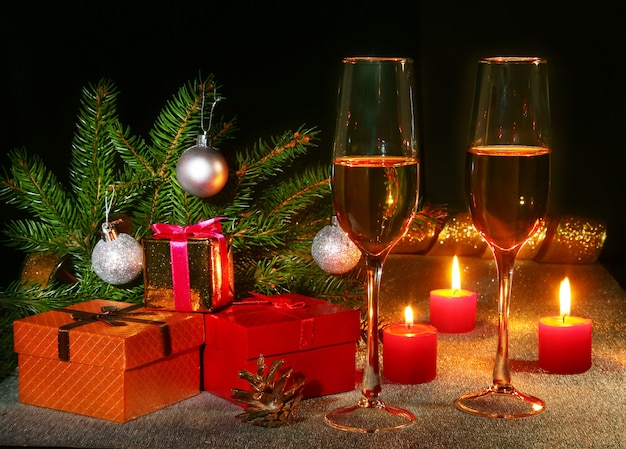 Composição de Natal com copo de champanhe espumante vinho ou conhaque, velas de Natal, bolas coloridas, caixa de presente e árvore em uma decoração de ano novo espumante.