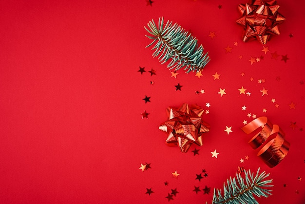 Composição de natal com espaço de cópia. galhos de árvores de abeto com decoração de natal e confetes festivos em fundo vermelho