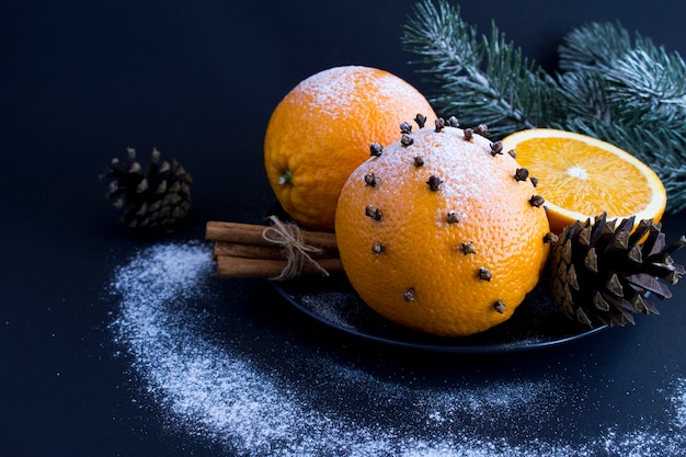 Composição de Natal com laranjas, cravo de especiarias e canela na placa preta sobre fundo preto. Fechar-se.