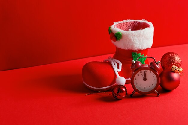 Composição de Natal com meia do Papai Noel, bolas de vidro de decoração festiva e despertador em um canto vermelho