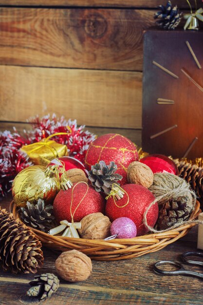 Composição de natal com presentes. cesta, bolas vermelhas, pinhas, flocos de neve na mesa de madeira. estilo vintage