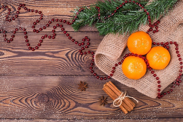 Composição de Natal com tangerinas, canela, anis estrelado e ramos de abeto, decoração de ano novo em um fundo de madeira. Vista superior, copie o espaço.